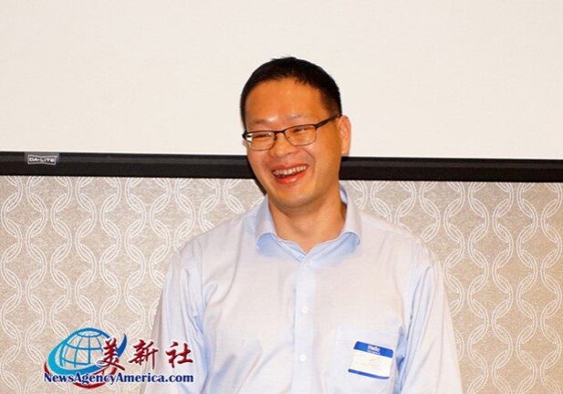 A man in glasses and a blue shirt is smiling